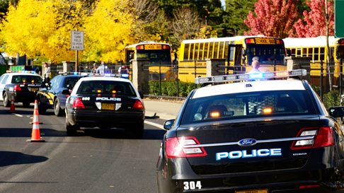 emergency scene at a school with police cars and school busses